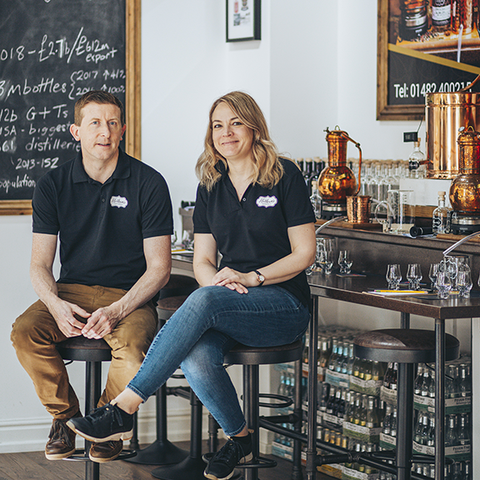 The founders of Hotham's Ltd Simon and Emma Pownall, sat on stools in their distillery